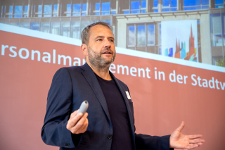 Arbeitsdirektor René Walther steht im Raum vor den neuen Mitarbeiterinnen und Mitarbeitern und stellt das Unternehmen vor.